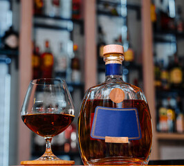 Elegant brandy bottle and glass on bar counter