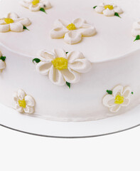 White fondant cake adorned with sugar daisies on a clean background