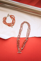 Red natural stone necklace and bracelet on a foil and magenta red background