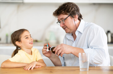 Father gives medicine to daughter to drink
