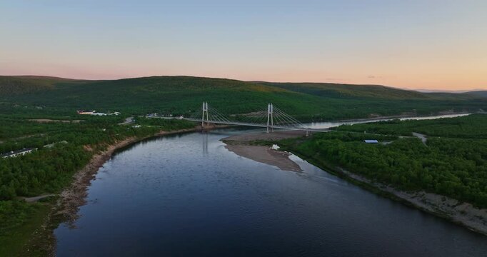 Aerial descending shot above the Tenojoki river with the Sami bridge background