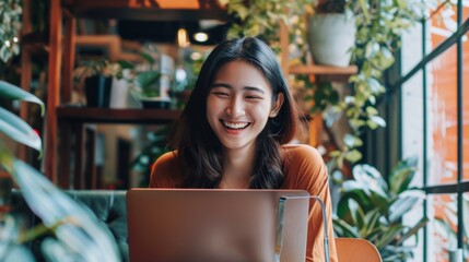 Joyful young woman smiling while working on a laptop in the office.