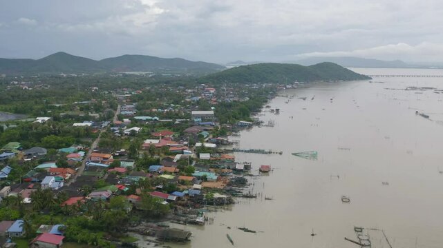 Aerial view of fishing trap net in canel with fisherman urban city village town houses, lake or river. Nature landscape fisheries and fishing tools at Pak Pha, Songkhla, Thailand. Aquaculture farming