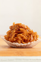 Close-up of a Colombian coconut candy in a paper capsule on a wooden table. Cocada. Image with copy space.