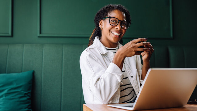 Happy black woman smiling while working on her laptop