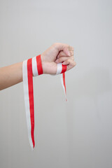 A woman's hand holds a red and white ribbon as a symbol of the Indonesian flag. Isolated on white background