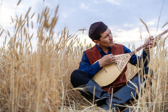 Kazakh, a man in Kazakh national dress playing dombra in the steppe. Kazakhstan. Central Asia. Nomads. | Казах, мужчина в казахской национальной одежде играет на домбре в степи. Казахстан.Средняя Азия