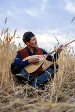 Kazakh, a man in Kazakh national dress playing dombra in the steppe. Kazakhstan. Central Asia. Nomads. | Казах, мужчина в казахской национальной одежде играет на домбре в степи. Казахстан.Средняя Азия