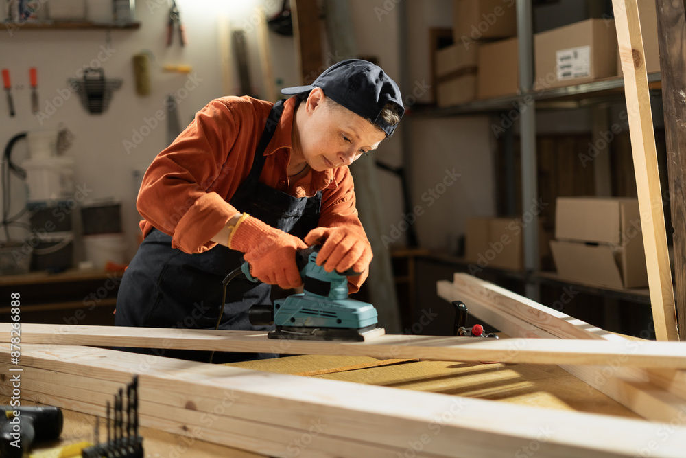 Wall mural professional female carpenter wears safety gloves using wood polishing machine grinding sanding wood