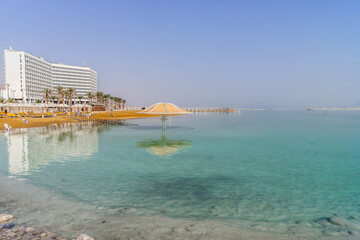 The resort town of Ein Bokek, Israel, with the beach umbrella, the waterfront, a hotel, and the beautiful turquoise water.
