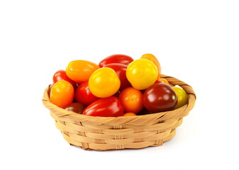 Different sorts of tomatoes in a woven basket isolated on white background.