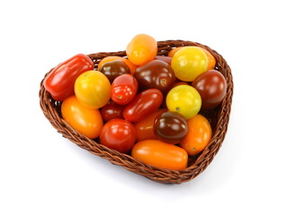 Different sorts of tomatoes in a woven basket isolated on white background.