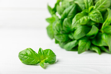 Green basil leaves on a textured wooden background. Kitchen herbs, spices. Fresh green organic basil. Vegan. Greens for salad. Place for text. Copy space.
