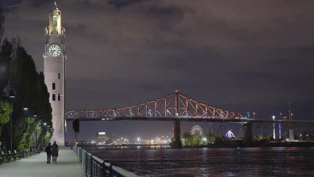 Old Port of Montreal Clock Tower and Jacques Cartier Bridge illuminated at night. Montreal, Quebec, Canada.