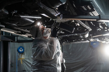 The master sprays an anti-corrosion compound on the bottom of the car. 