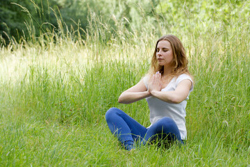 Woman meditating with eyes closed, doing breathing exercises, relaxing body and mind. Mental health...