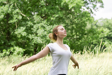 A woman rests in nature with her arms outstretched, the concept of emotional balance