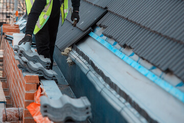 Construction Worker Installing New Roof Tiles On Building