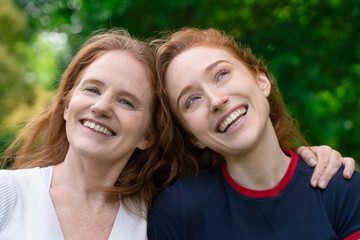 Two Red-Haired Women Smiling and Looking Upwards in Green Park