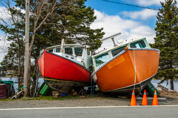 Commercial inshore fishing boats parked and propped up on land by the side of the road on St Margaret’s Bay in Nova Scotia room for text