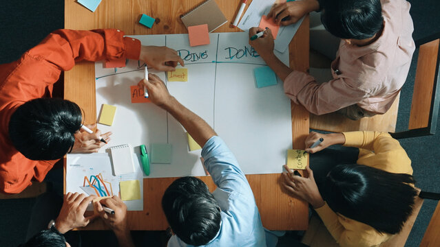 Top view of people writing and making scrum task board while writing marketing and planning strategy at colorful sticky notes. Smart team manage work performance by using kanaban board. Convocation.