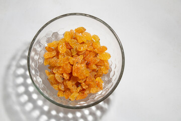 top view Yellow raisins in an open glass bowl, isolated on white, with bowl shadow, negative space