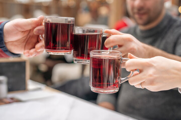 Three People Toasting With Red Wine in Glass Mugs at Christmas Market