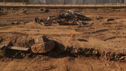 A construction site with debris and tire tracks in the dirt