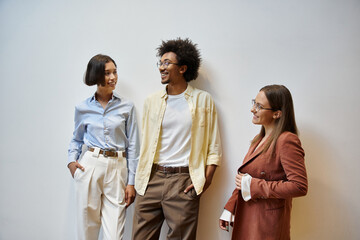 Three colleagues stand in an office, engaging in a friendly conversation.