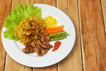 Fried noodles with black pepper seasoned Chicken Steak on a wooden table