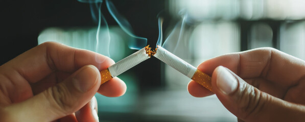 A person breaking a cigarette in half to quit smoking