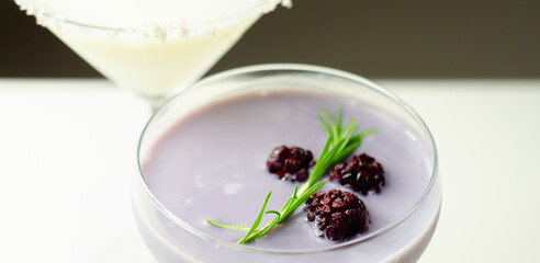 A glass of purple liquid with blackberries floating on top