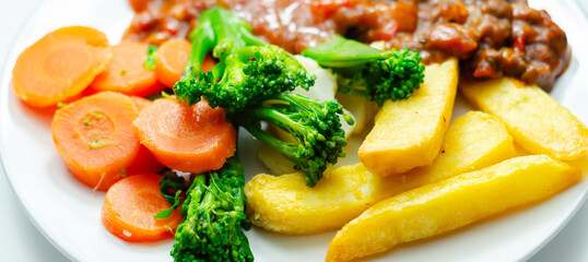 A plate of food with meat, french fries, and vegetables