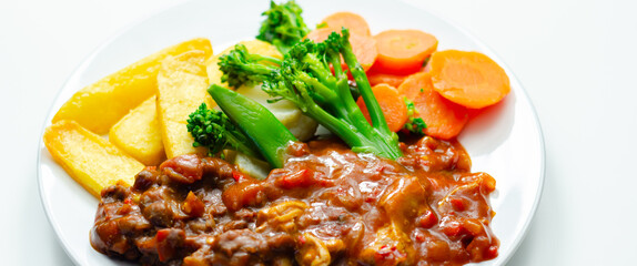 A plate of food with meat, french fries, and vegetables
