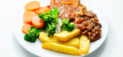 A plate of food with meat, french fries, and vegetables