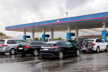 Multiple cars queue waiting refuel at gas station overcast cloudy sky background n rainy day....