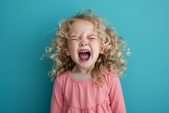 curly haired girl screaming and throwing tantrum against teal background