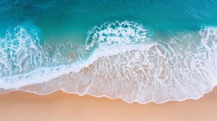 Fototapeta premium Aerial view of stunning turquoise ocean waves gently crashing onto a pristine sandy beach, creating a serene and tranquil coastal scene.