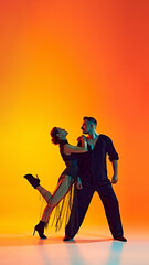Romantic dance style. Artistic and talented man and woman dancing bachata against gradient yellow orange background in neon light. Concept of dance, performance, art, entertainment