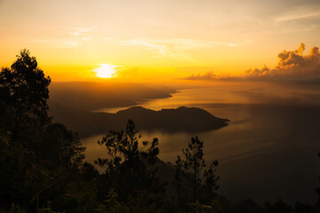 This captivating photo captures a golden sunrise over Lake Toba in Sumatra, Indonesia. The serene waters and lush hills create a tranquil scene, perfect for nature and travel enthusiasts seeking a bre