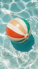 Obraz premium A colorful beach ball floating in the water of an outdoor swimming pool, with clear blue and white tiles visible beneath it.