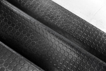 Black rubber mat with a non-slip pattern covers an industrial stairway