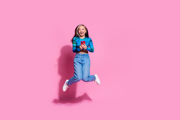 Full length photo of charming positive woman wear blue top jumping high communicating modern gadget empty space isolated pink color background