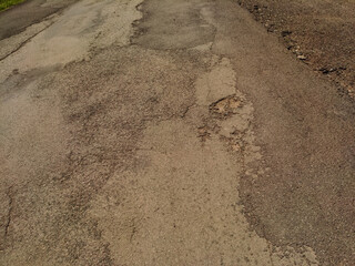 A close-up shot of a cracked and weathered asphalt road surface