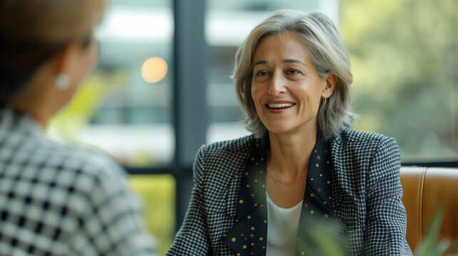 Two women in suits conversing at a restaurant - Powered by Adobe