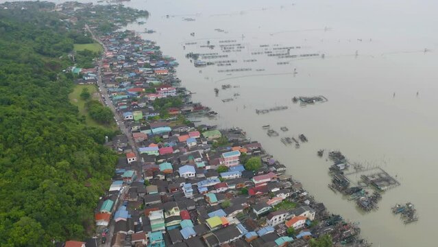 Aerial view of fishing trap net in canel with fisherman urban city village town houses, lake or river. Nature landscape fisheries and fishing tools at Pak Pha, Songkhla, Thailand. Aquaculture farming