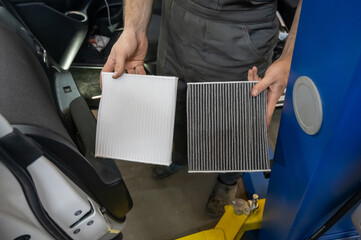 Mechanic holding old and new cabin air car filters. 