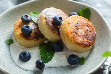 Cottage cheese pancakes with cream sauce and blueberries. syrniki 