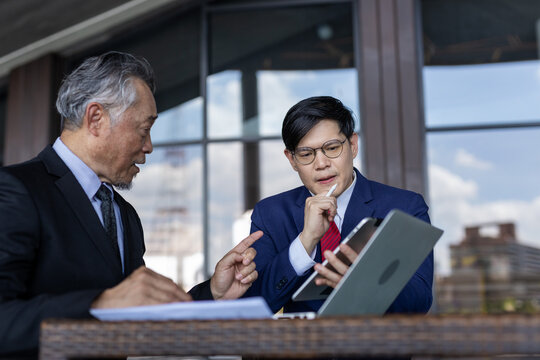 Asian multi generation business men wear suit working together. Senior and young businessman discussing agreements to meetings with partners and connections. Discuss business strategy.