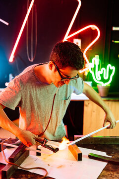 Man Bending Neon Tube With Torch in Workshop